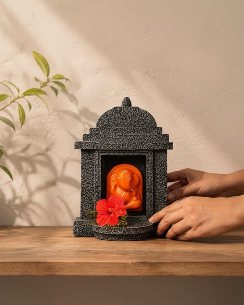 Two hands placing the shrine onto a wooden shelf.
